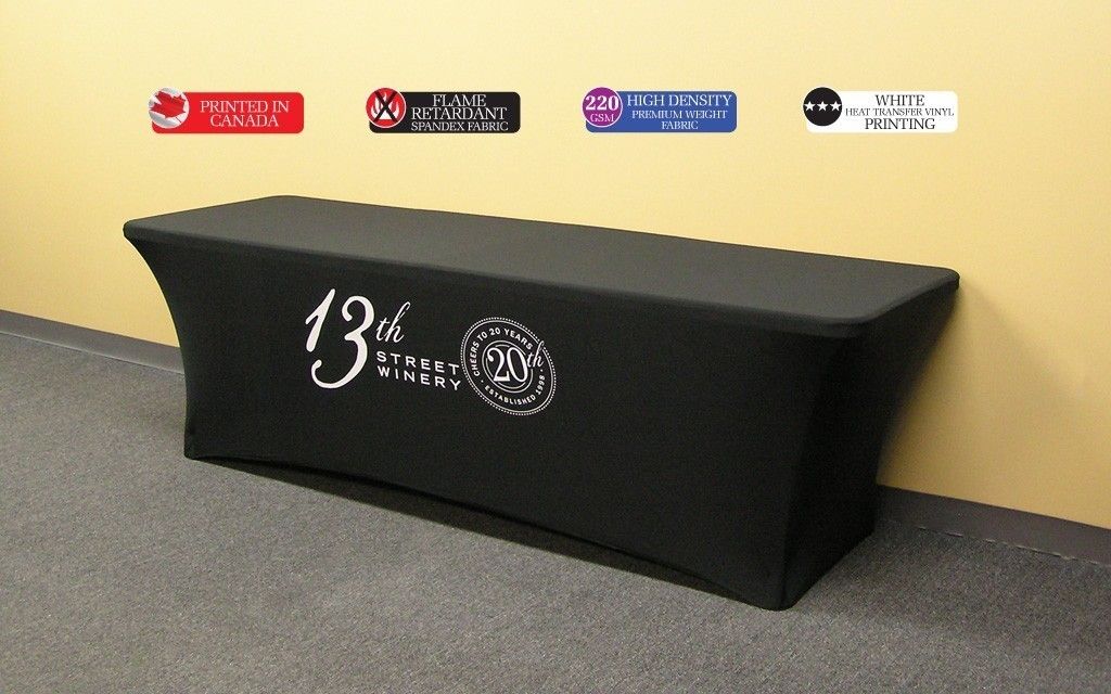 This 8 ft black fire resistant economy spandex stretch table cover displays a simple 1 colour white print on the front for an economical yet stylish table display